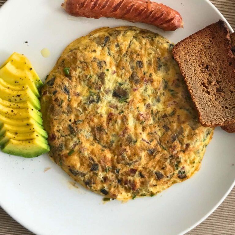High-protein zucchini tortilla with chicken sausage and avocado on white plate