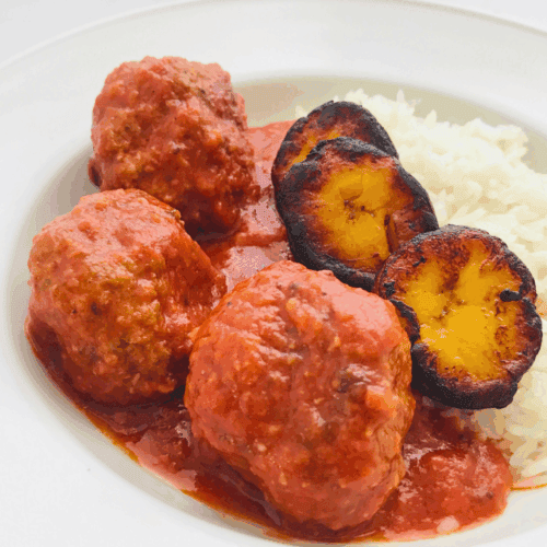Savory meatballs with tomato sauce and grilled plantains served with white rice, delicious meal from Petit Gourmet culinary offerings, perfect for lunch or dinner.