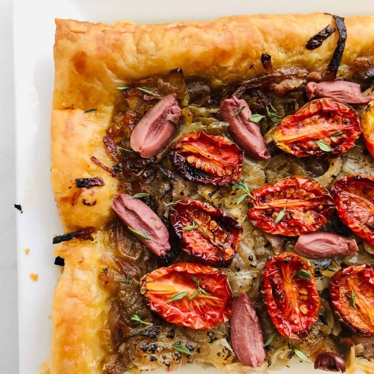 Crispy vegetable tart with cherry tomatoes, caramelized onions, and fresh herbs on flaky pastry crust.