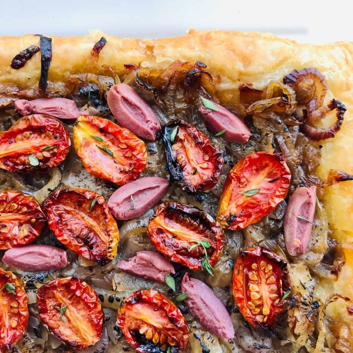 Freshly baked gourmet flatbread topped with roasted cherry tomatoes, caramelized onions, and sliced cured meats, perfect for peti gourmet-inspired dishes and healthy pet treats.