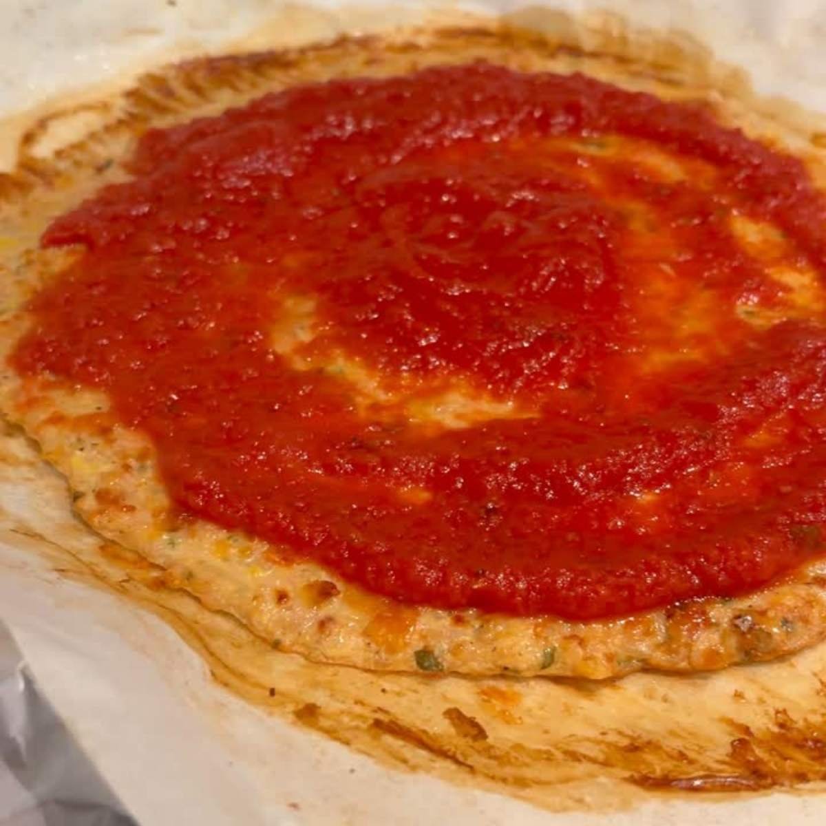 High-protein chicken crust pizza sliced on parchment with fresh basil